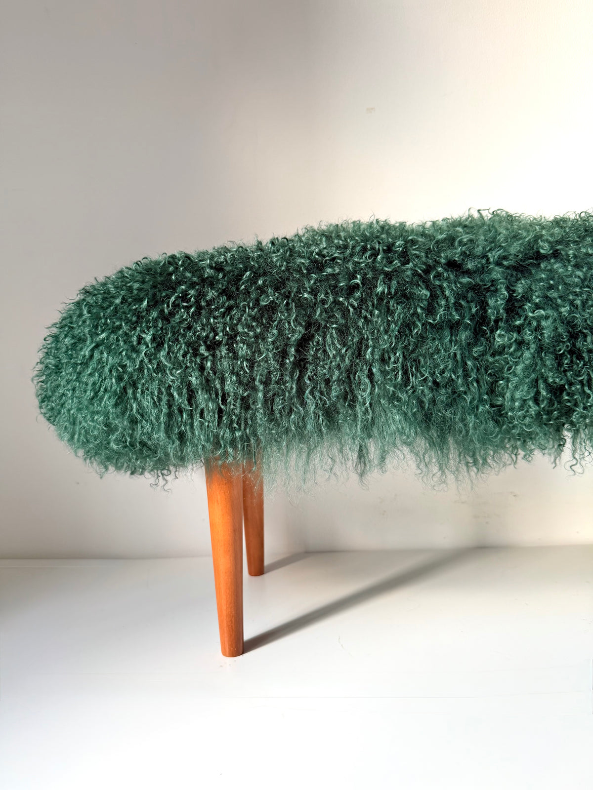 Handmade green Mongolian fur single bench on solid wood tapered legs, photographed in our London studio