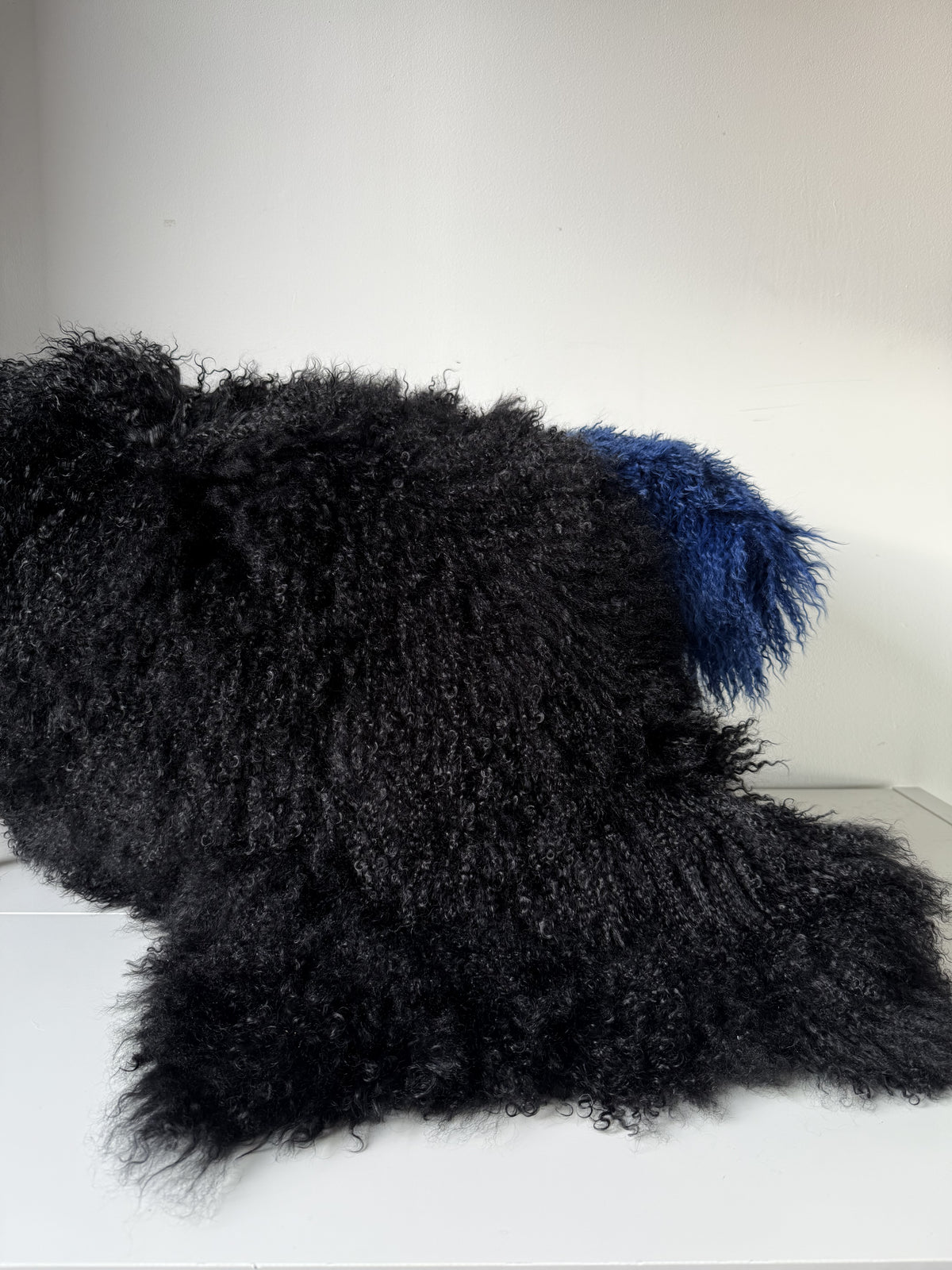 Black Mongolian fur single throw draped over a bench