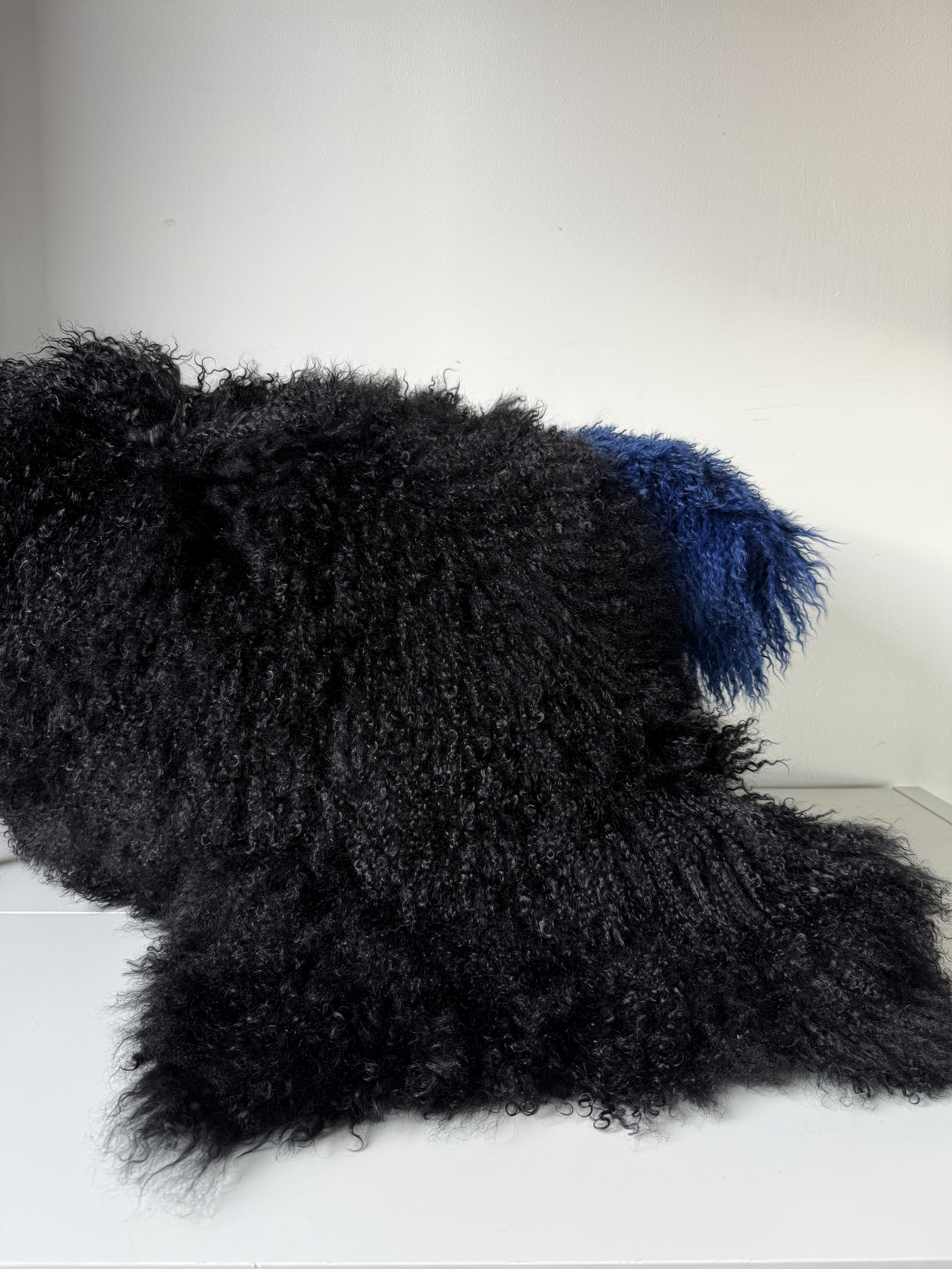 Black Mongolian fur single throw draped over a bench