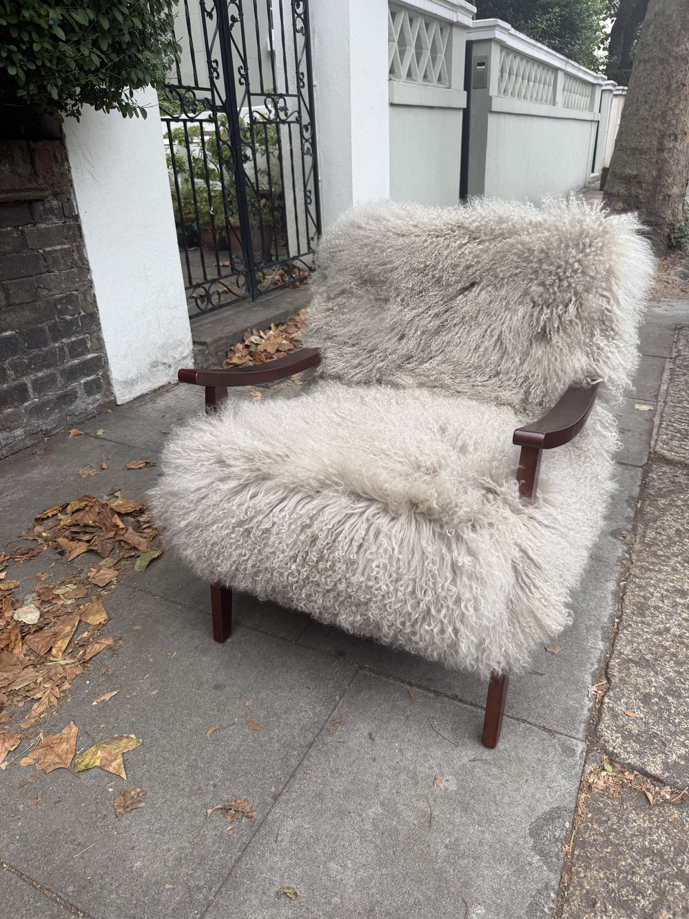 Handmade almond Mongolian fur accent chair with curved walnut arms, front view
